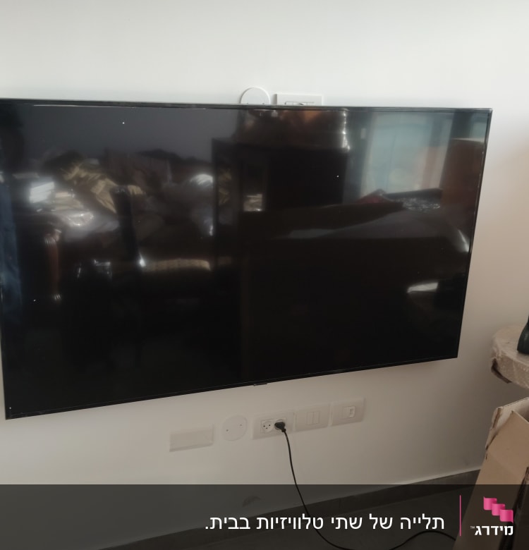 טלוויזיה תלויה על הקיר עם כבל חשמל מחובר